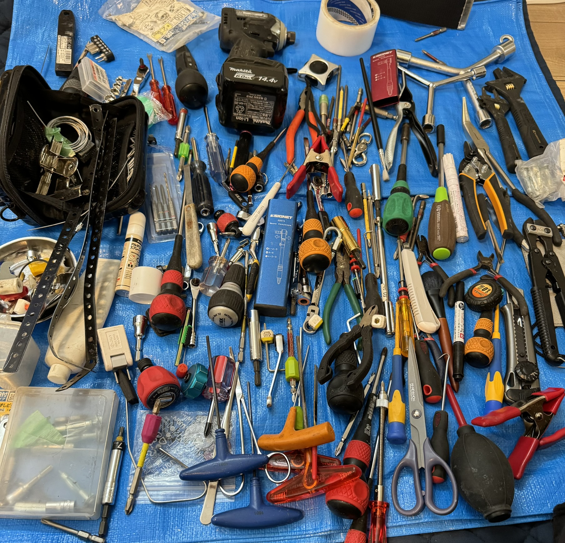 青いシートにドライバー、ラチェット、ビット、ペンチなどを並べた実際の道具写真